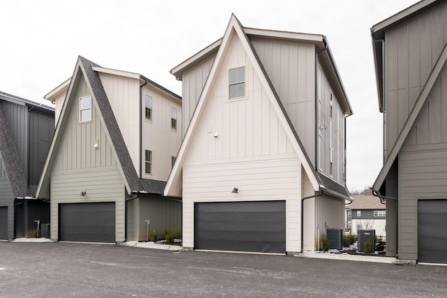 view of front of property with cooling unit, board and batten siding, and roof with shingles