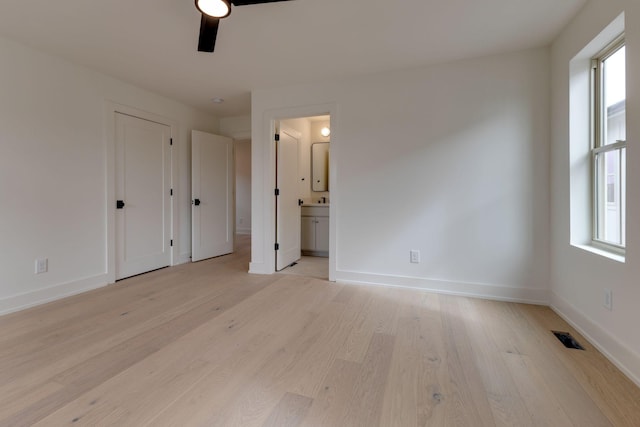 unfurnished bedroom featuring light wood-style flooring, multiple windows, visible vents, and baseboards