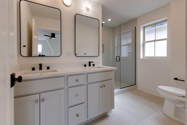 bathroom featuring double vanity, a shower stall, toilet, and a sink