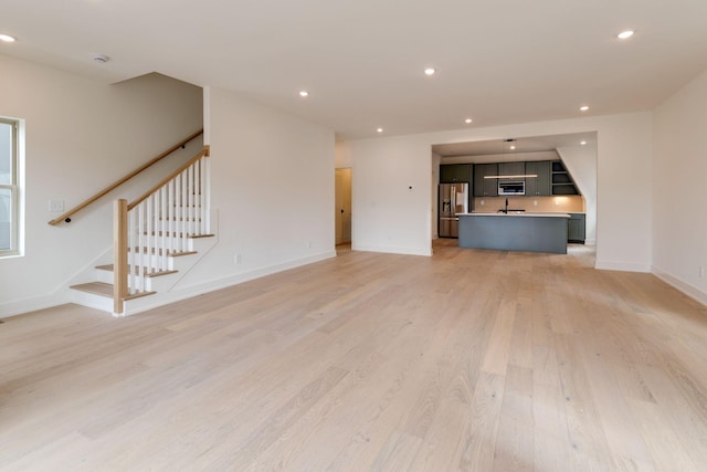 unfurnished living room with light wood-type flooring, stairway, baseboards, and recessed lighting