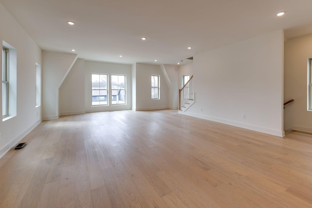 unfurnished living room featuring visible vents, baseboards, light wood-style flooring, stairway, and recessed lighting