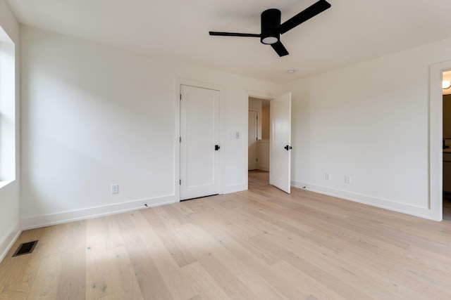 unfurnished bedroom featuring ensuite bathroom, light wood finished floors, visible vents, and baseboards