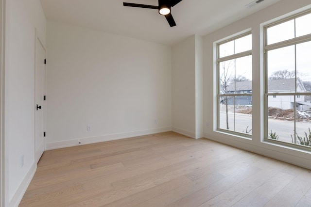 unfurnished room featuring light wood-style floors, visible vents, baseboards, and a ceiling fan