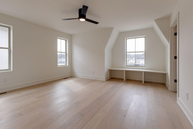 additional living space with baseboards, a ceiling fan, a wealth of natural light, and light wood-style floors