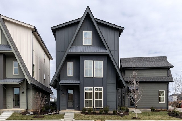 view of front facade featuring metal roof, a shingled roof, board and batten siding, and a front yard