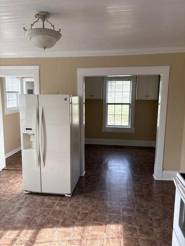 kitchen with ornamental molding, white refrigerator with ice dispenser, stove, and a healthy amount of sunlight