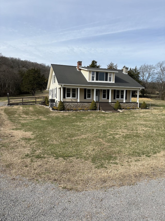 view of front of home featuring covered porch, a front lawn, a chimney, and fence