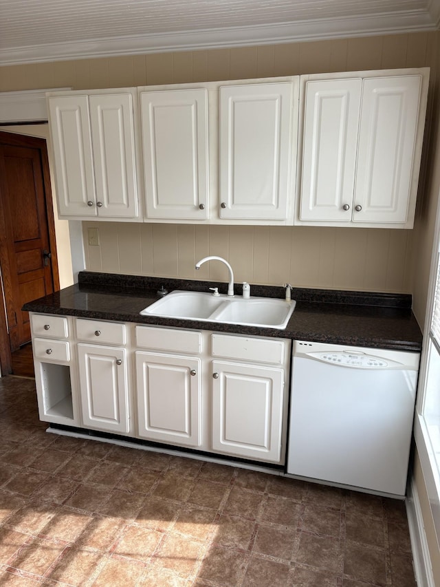 kitchen featuring dark countertops, white dishwasher, a sink, and white cabinets