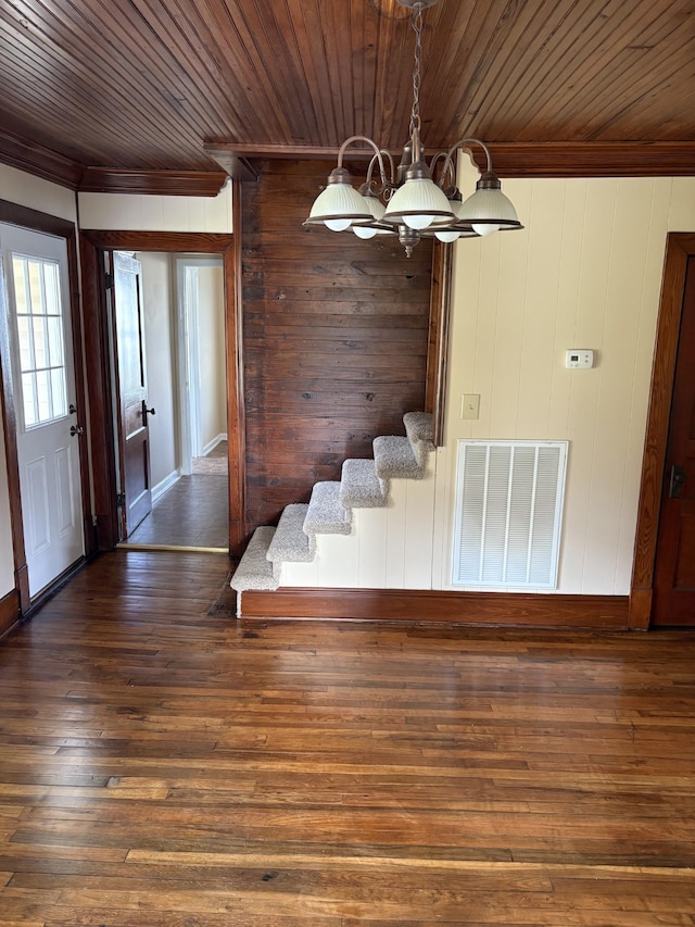 foyer entrance featuring wooden ceiling, dark wood-type flooring, visible vents, ornamental molding, and an inviting chandelier