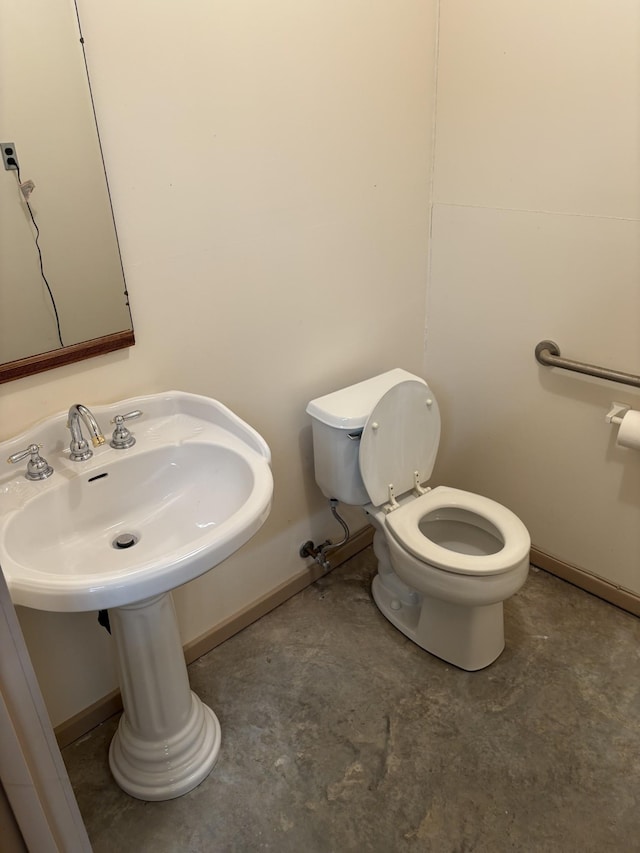 bathroom with concrete flooring, baseboards, and toilet