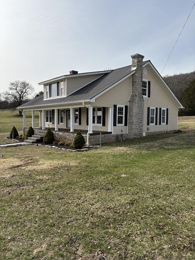 view of front of house featuring covered porch, a front lawn, and a chimney