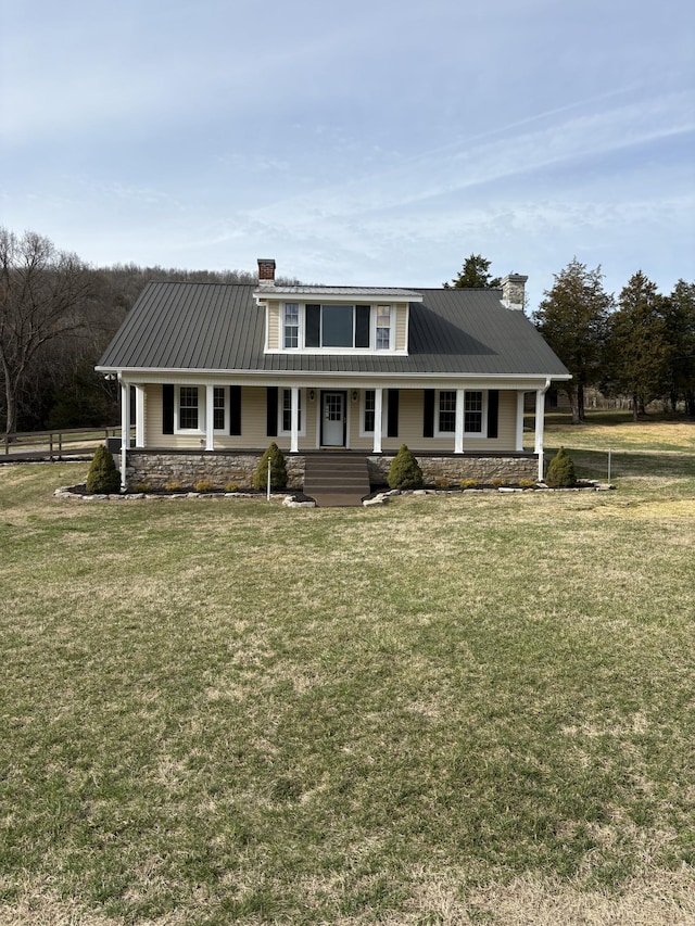 view of front facade featuring covered porch, metal roof, a chimney, and a front yard