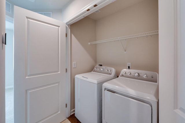 clothes washing area with laundry area, visible vents, and washer and clothes dryer