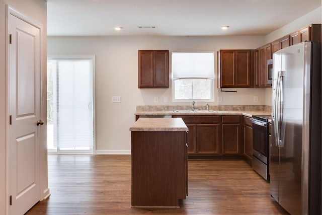 kitchen featuring visible vents, a kitchen island, stainless steel appliances, light countertops, and a sink