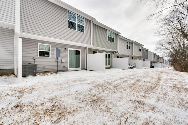 snow covered house featuring fence and central AC unit