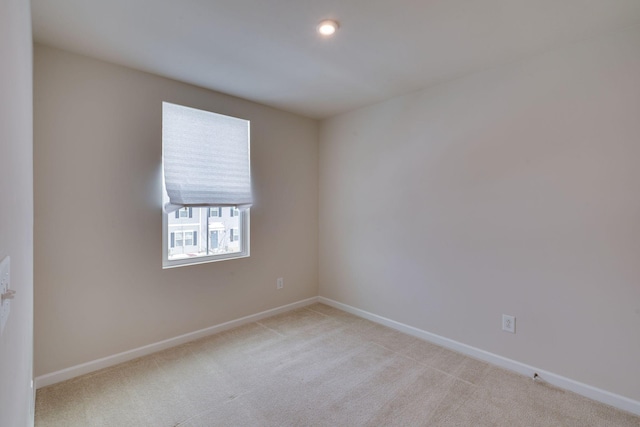 spare room with baseboards, recessed lighting, and light colored carpet