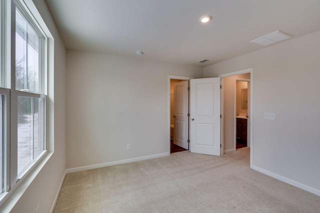 spare room with baseboards, a wealth of natural light, visible vents, and light colored carpet