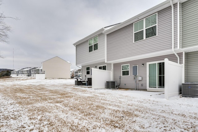 snow covered rear of property with central AC unit