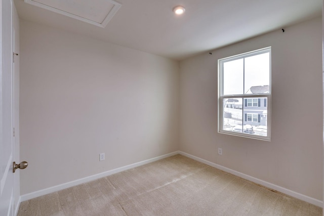 unfurnished room with attic access, light colored carpet, and baseboards