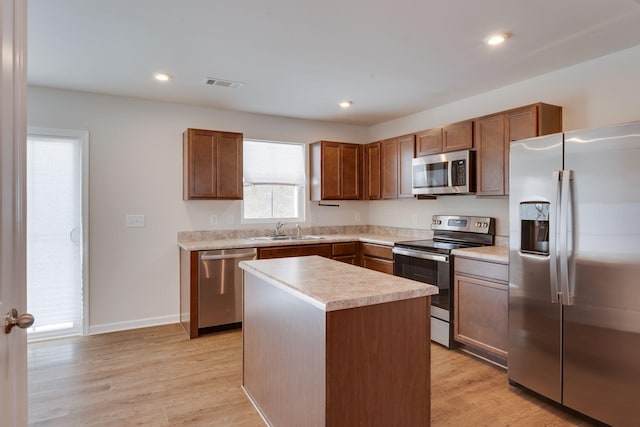 kitchen with light wood finished floors, stainless steel appliances, light countertops, visible vents, and a kitchen island