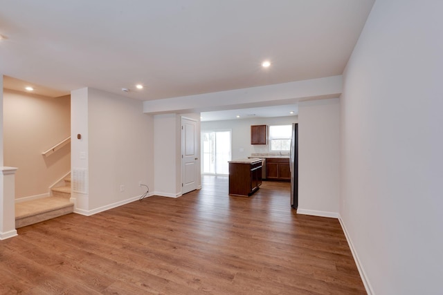 unfurnished living room with recessed lighting, wood finished floors, baseboards, and stairs