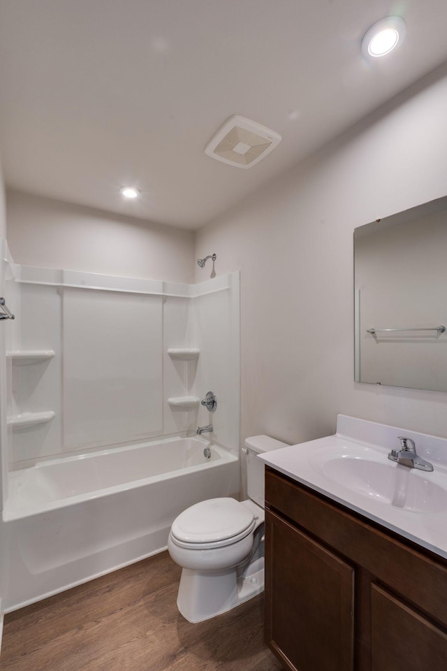 full bath with toilet, wood finished floors, vanity, washtub / shower combination, and recessed lighting