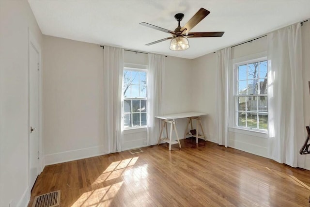 interior space featuring light wood-style floors, baseboards, visible vents, and ceiling fan