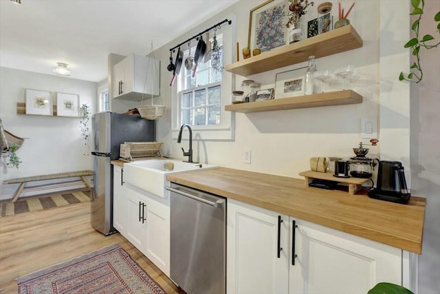 kitchen featuring butcher block counters, a sink, white cabinetry, appliances with stainless steel finishes, and open shelves