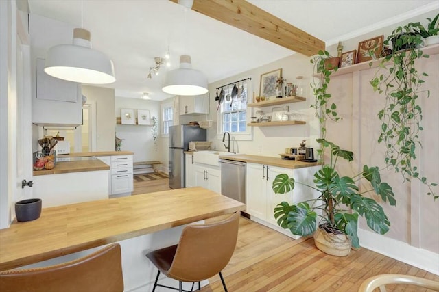 kitchen featuring decorative light fixtures, stainless steel appliances, white cabinetry, open shelves, and wooden counters