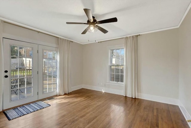 empty room featuring crown molding, wood finished floors, and baseboards