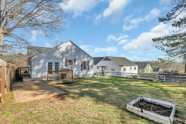 back of property featuring a lawn, a fenced backyard, a patio area, a garden, and a wooden deck