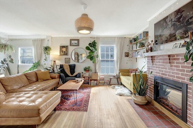 living area featuring ornamental molding, a brick fireplace, and wood finished floors