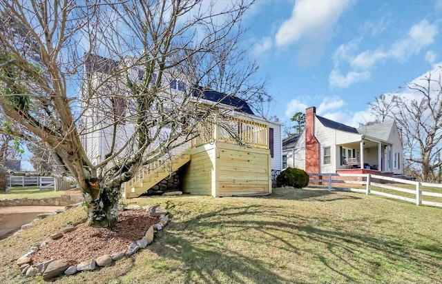 view of home's exterior featuring fence, stairway, and a lawn