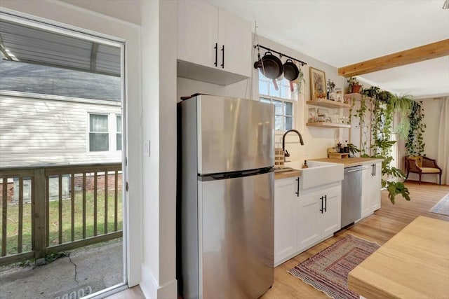 kitchen featuring open shelves, appliances with stainless steel finishes, beamed ceiling, white cabinetry, and wooden counters