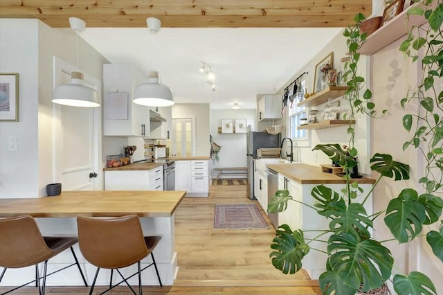 kitchen featuring white cabinets, butcher block counters, a kitchen breakfast bar, a peninsula, and open shelves