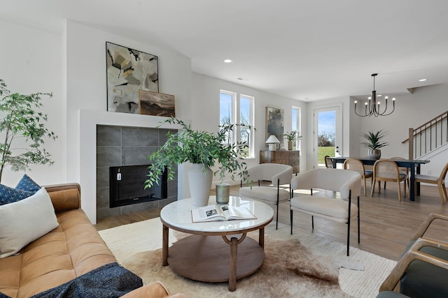 living area with recessed lighting, an inviting chandelier, wood finished floors, and a tile fireplace