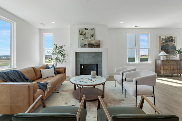 living room with recessed lighting, plenty of natural light, light wood-style floors, and a tile fireplace