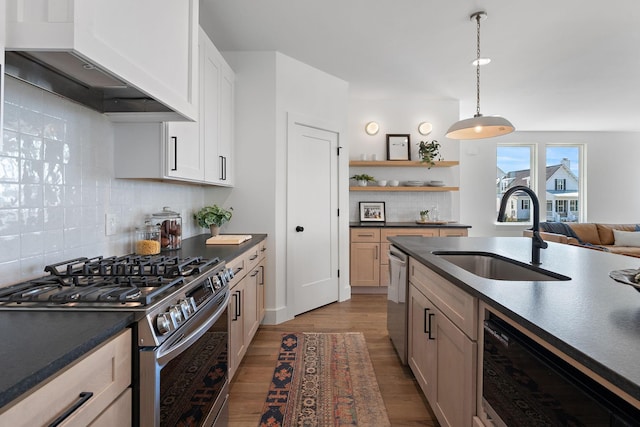 kitchen featuring dark countertops, stainless steel appliances, wall chimney exhaust hood, and a sink