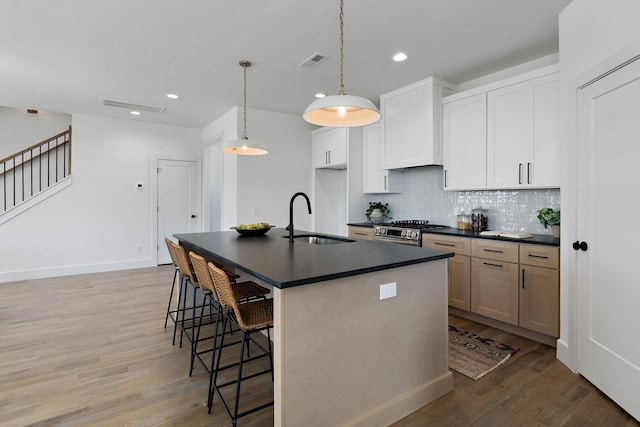 kitchen with dark countertops, visible vents, stainless steel gas range, and a sink