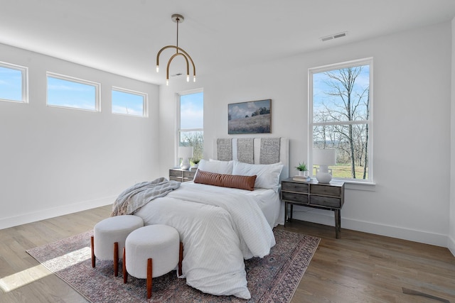 bedroom with visible vents, multiple windows, baseboards, and wood finished floors