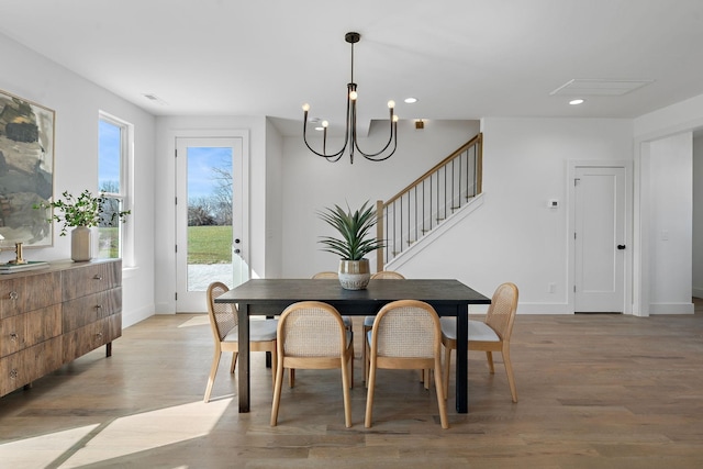 dining space with light wood finished floors, baseboards, a chandelier, stairs, and recessed lighting