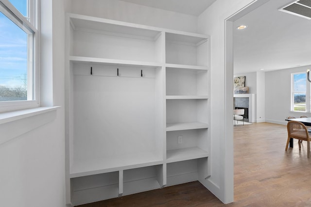 mudroom featuring visible vents, built in shelves, wood finished floors, and a fireplace