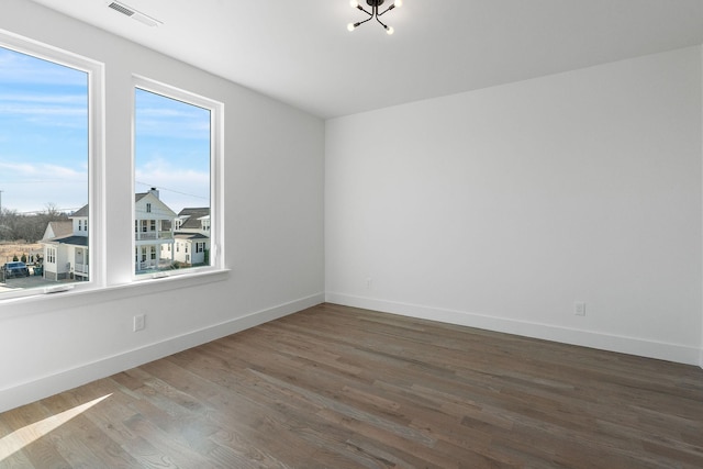 unfurnished room with visible vents, baseboards, and wood finished floors