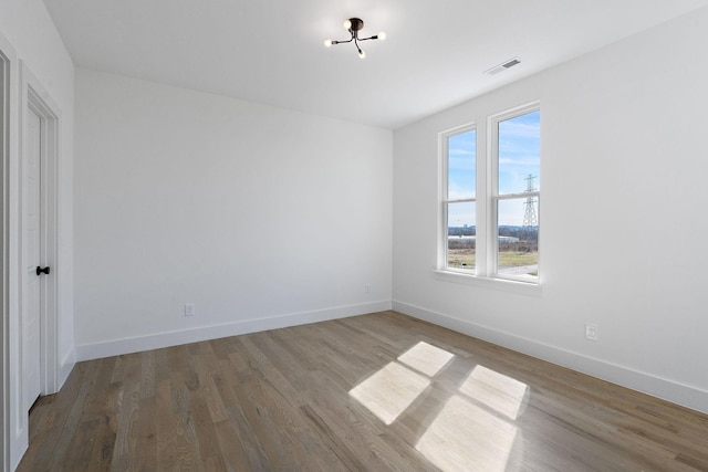 spare room featuring visible vents, baseboards, and wood finished floors