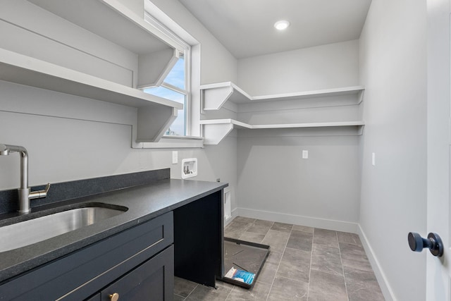 kitchen featuring open shelves, dark countertops, baseboards, and a sink