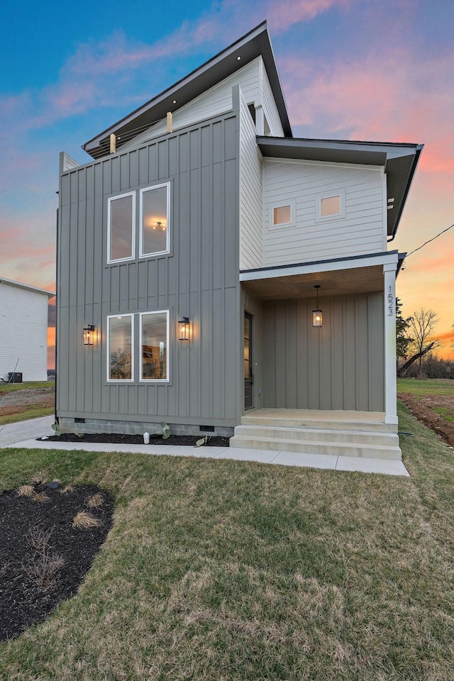 back of house featuring a lawn, board and batten siding, and crawl space