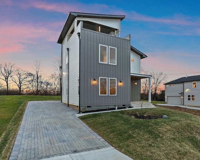 contemporary home featuring crawl space, a lawn, and board and batten siding