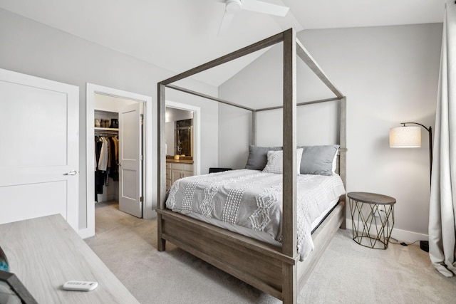 bedroom featuring light carpet, lofted ceiling, a walk in closet, and connected bathroom