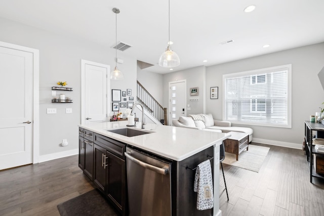 kitchen with decorative light fixtures, light countertops, a sink, an island with sink, and dishwasher