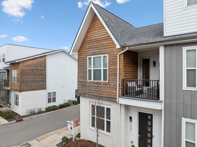 exterior space featuring board and batten siding, cooling unit, a shingled roof, and a balcony